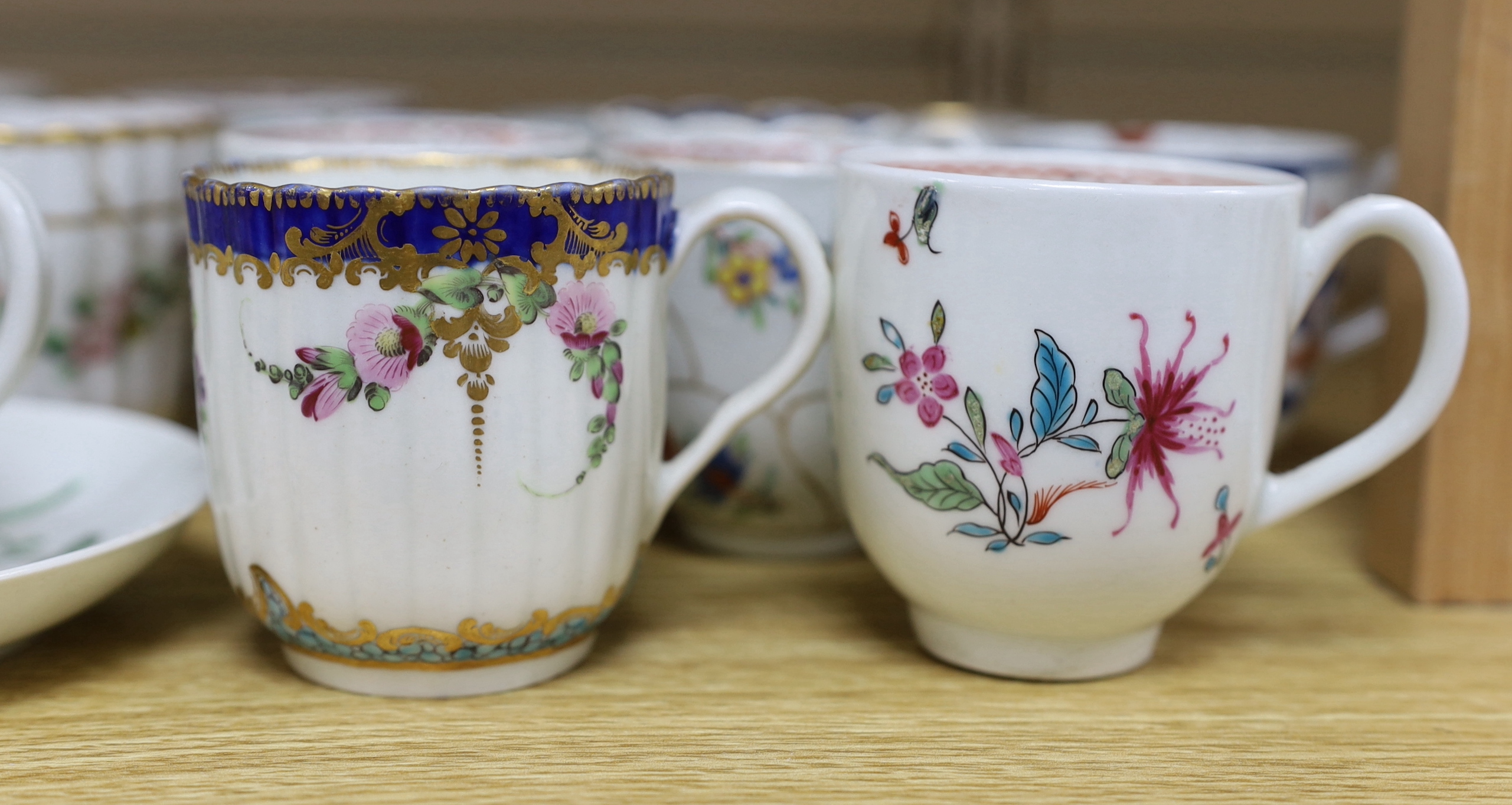 A collection of late 18th century Worcester and Lowestoft coffee cups and a saucer, many hand painted with flowers, the largest 12cm in diameter